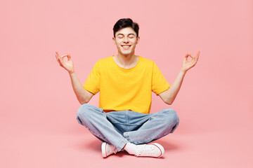 Full body young man wearing yellow t-shirt casual clothes sits hold spreading hands in yoga om aum...