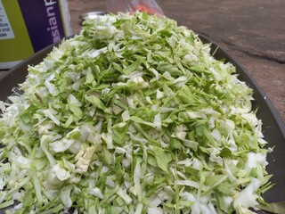 Finely chopped cabbage vegetable in a plastic container, Very finely chopped small and long cabbage green vegetable in a plastic pot,Fresh cabbage vegetable cut Stock Photos and Images,