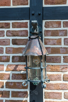 Forged iron street lamp on brick wall selective focus closeup