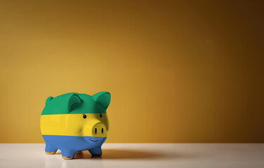 Piggy bank with painting of Gabon flag. The problem is in the economy. Economic crisis. Saving money concept.