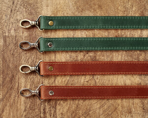 Collection of leather bag straps with carabiners on wooden surface