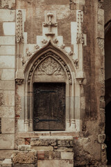 Fototapeta na wymiar brown wooden door on gray concrete building. The architectural details of the Corvin Castle in Hunedoara, Romania