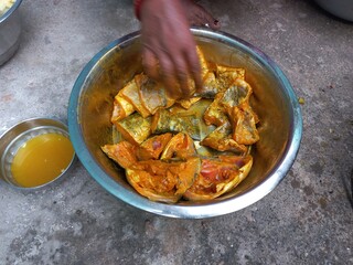 Raw cut Fish pieces,Raw cut Fish pieces mixing turmeric oil salt a woman hand on,Cutting raw fish on an Aluminium container,