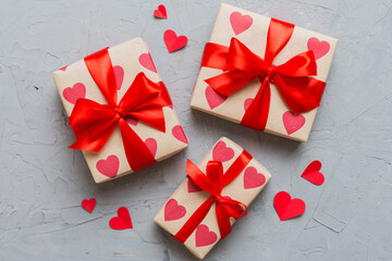 Top view photo of valentine day decorations gift box with red ribbon bow on colored background....