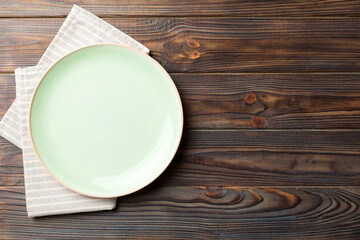 Top view on colored background empty round green plate on tablecloth for food. Empty dish on napkin...