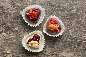 chocolate sweets in the form of a heart with fruits and nuts on a colored background. top view with space for text, holiday concept