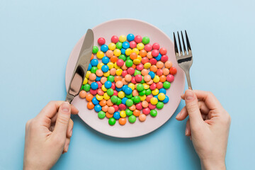 the girl holds cutlery in her hands and eats sweets in a plate. Health and obesity concept, top...