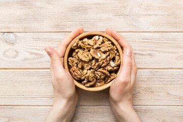 Woman hands holding a wooden bowl with walnut nuts. Healthy food and snack. Vegetarian snacks of...