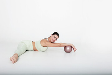 A beautiful young woman is engaged in muscle stretching. Stretching muscles with a ball. Healthy lifestyle. Fitness or Pilates. Copy space. Isolated object.