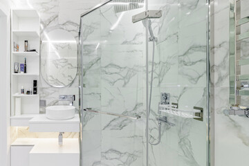 Simple white painted bathroom with lozenge shaped bath, glazed panel shower cubicle