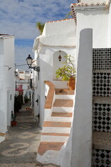A picturesque narrow cobbled alley in Frigiliana, Axarquia, Malaga province, Andalusia, Spain, with traditional whitewashed little houses and and a decorated cobbled pavement
