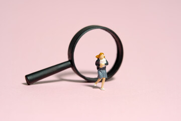 Miniature people toy figure photography. A girl pupil student running in front of magnifier glass....