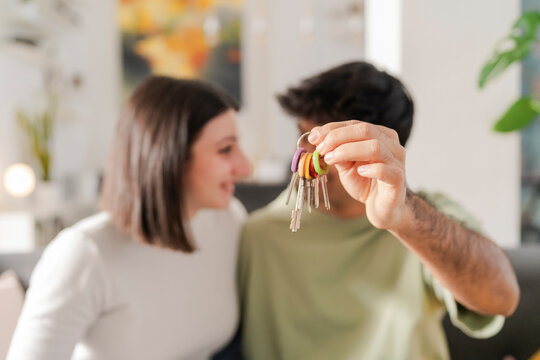 Young couple closely examining a set of house keys, focused and content with their recent purchase
