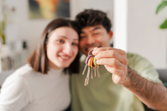 Ecstatic young couple smiling and holding up a set of new house keys, marking a joyous occasion