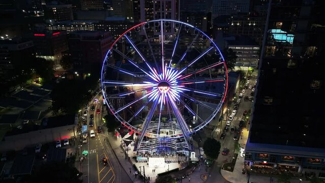 Incredible light effects of large Ferris Wheel and buildings in urban borough in evening city. Atlanta, Georgia, USA