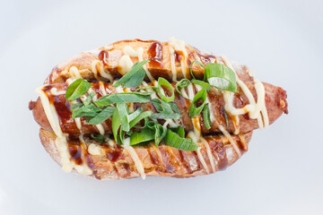 Close up top view of veal sausage hot dog in sweet potato bread with spring onions on white plate