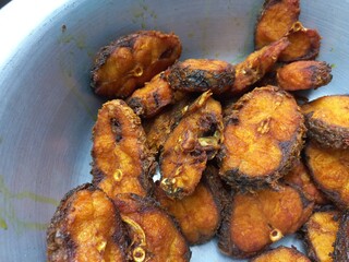 Dry tarmerik salt masala fish fry is a simple tasty delicious and flavourful fish fry in Aluminum pot,Hot Fried Fish on a Almuniyam container with Hot Oil,Hot bubbly and so delicious Fish,brown Fish 