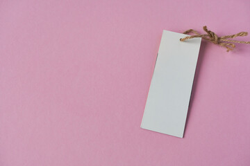 Blank white price tag with lanyard on pink background with space for text. Template for design.
