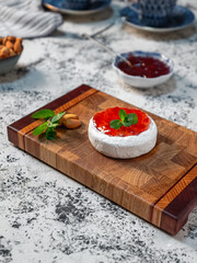 Vertical image of a dessert made from Camembert cheese and strawberry jam.
