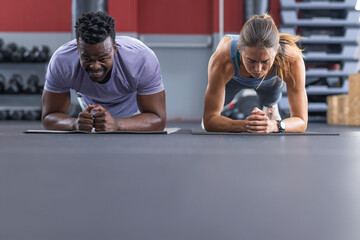 Fit diverse couple doing planks at the gym