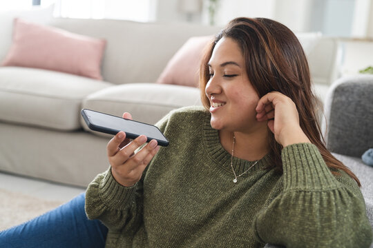 Young plus size biracial woman enjoys a video call at home - Powered by Adobe