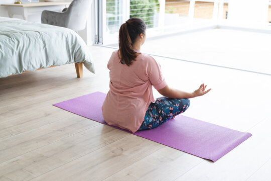 Young plus size biracial woman practices yoga at home, with copy space unaltered