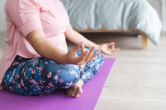 Young plus size biracial woman practices yoga at home, with copy space unaltered - Powered by Adobe