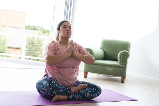 Young plus size biracial woman practices yoga at home - Powered by Adobe