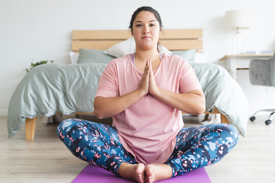 Young plus size biracial woman practices yoga at home