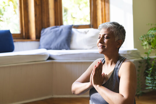 A mature biracial woman practices yoga at home, with copy space - Powered by Adobe