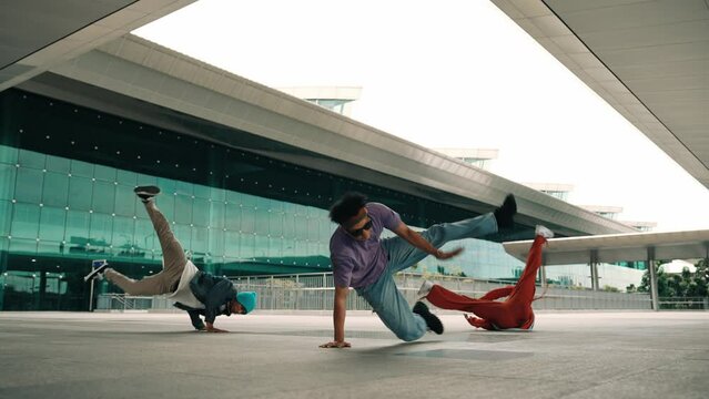 Group of diverse hipster or street dancer doing head spin in front of mall. Happy energetic break dancer practice b-boy step dancing with friends. Outdoor sport 2024. Street dancer concept. Sprightly.