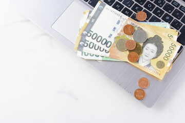 韓国の通貨、ウォンKRW（紙幣と硬貨）とノートパソコン
