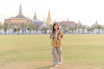 Fototapeta premium A Traveler Asian woman in her 30s exploring Wat Pra Kaew. From stunning architecture to friendly locals, she cherishes every moment, capturing it all in her heart and camera for years to come.