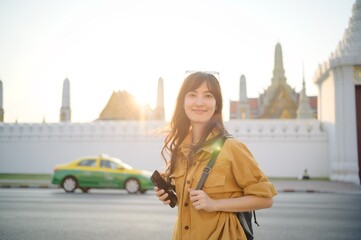 Traveler asian woman in her 30s stands bathed in the golden glow of sunset, embracing the freedom of exploration. on summer holiday weekend vacation trip in Bangkok, Thailand