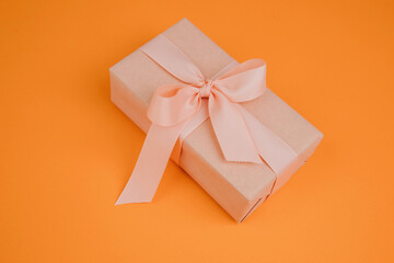 Greeting background. Gift wrapping in soft pink paper on a orange background with copy space. Top view
