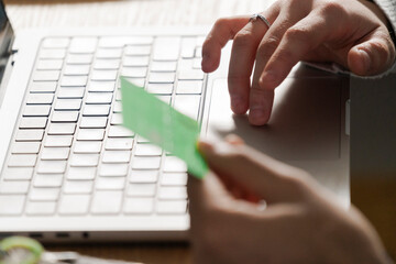 hand placing a credit card on a laptop trackpad, symbolizing a secure online transaction from home