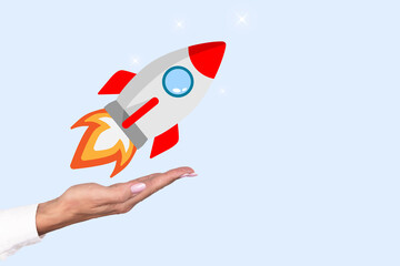 Startup concept. Business woman's hand launches a rocket on a blue background. Copy space.