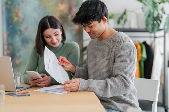 Couple collaborating on financial paperwork with laptop and credit cards on table