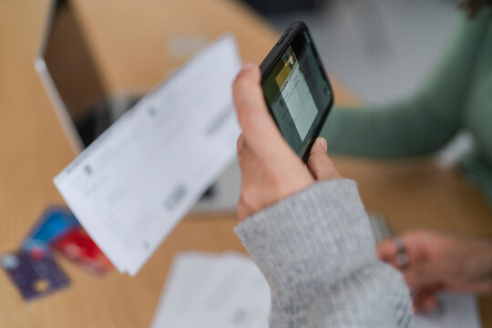Close-up of a couple using a smartphone to scan a bill to pay with home banking at a home office