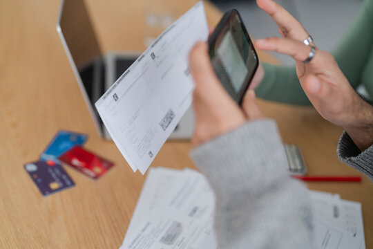 Close-up of a couple using a smartphone to scan a bill to pay with home banking at a home office