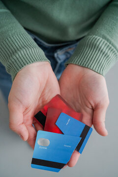 A close-up of a woman's hands holding pieces of cut credit cards, emphasizing a choice to manage finances or eliminate debt. It conveys a message of fiscal responsibility