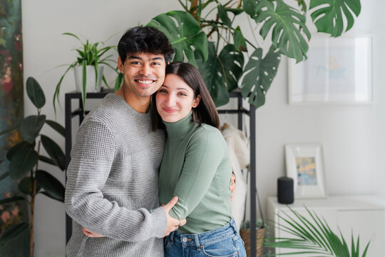 Smiling couple shares a joyful hug, capturing a moment of happiness and closeness in a homely atmosphere