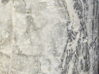 The texture of a gray marble stone with veins, cracks and inclusions