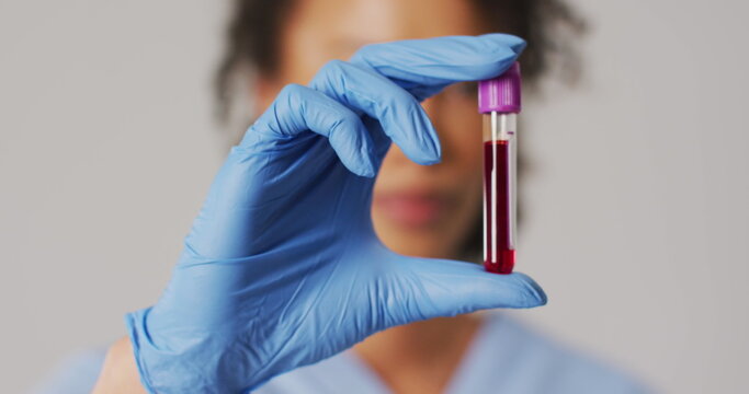 Image of mathematical equations over biracial female doctor with test tube