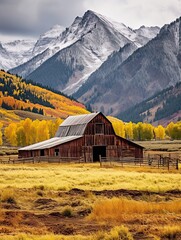 Snow-Covered Rustic Barns Amidst Fall Foliage and Majestic Mountain Scenery