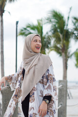Pretty muslim woman enjoying sun shine at the beach wearing cardigan.