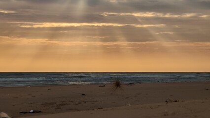 The volume light from the afternoon sun, piercing through the cloudy sky, creates a radiant line of...