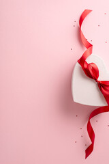 Perfect gift idea for her: vertical top view of heart-shaped present wrapped with red bow,...