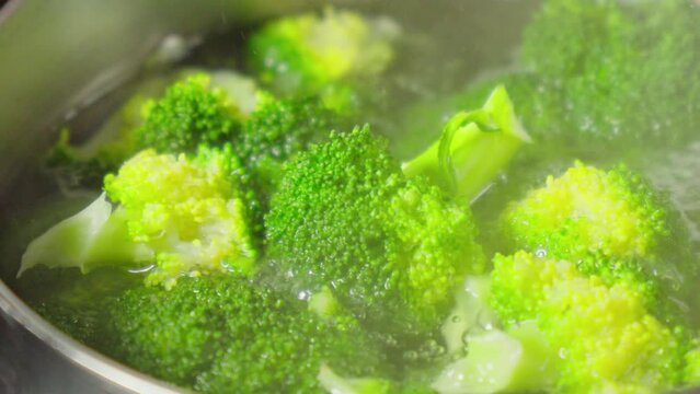 Fresh green broccoli florets gently boiling in a pot of water, releasing steam and filling the kitchen