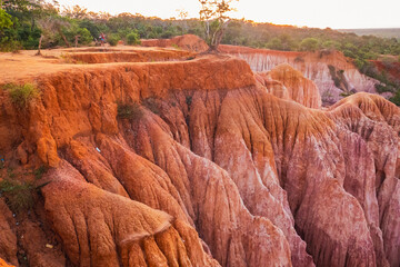 Tourists dwarfed by rock formations at Marafa Depression - Hell's Kitchen at sunset in Malindi,...